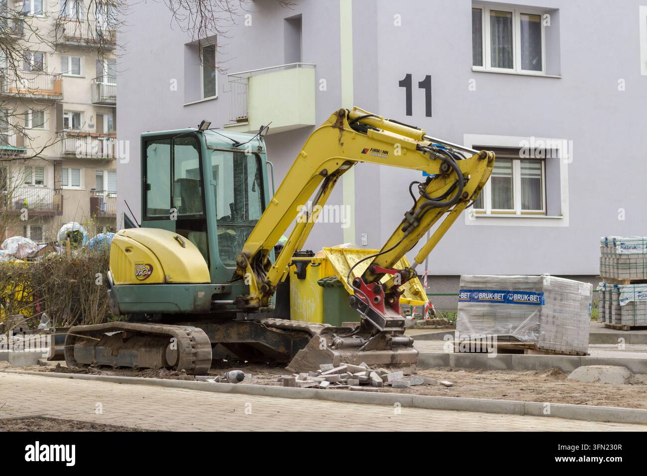 Gelbe Minibagger auf einer Baustelle neben einem Wohnhaus Stockfoto