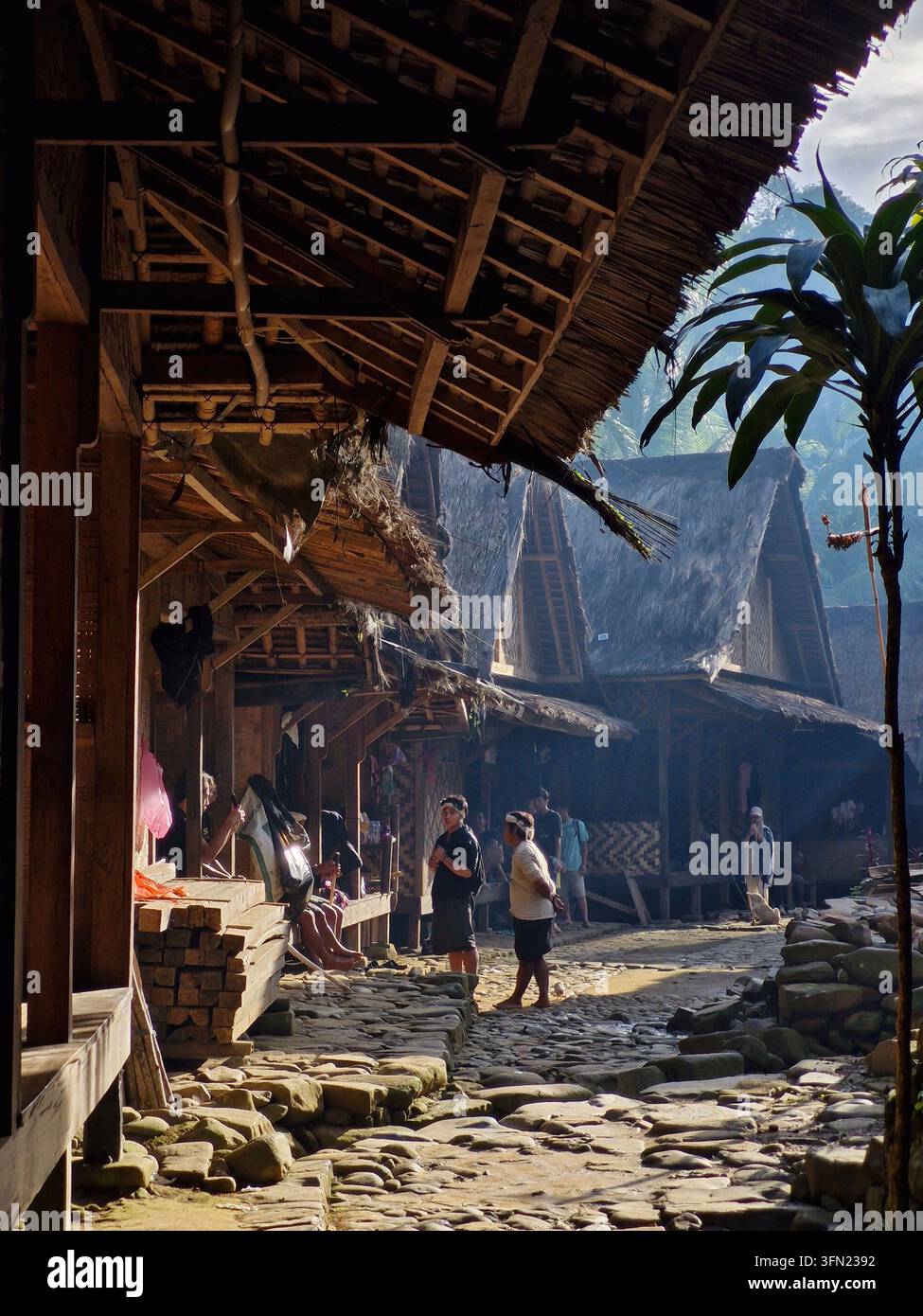Zwei Baduy-Menschen, die vor einem traditionellen Haus mit Blick auf das Baduy-Dorf in Lebak, Banten, Indonesien, sprechen. - Smartphone-aufgenommenes Stockfoto