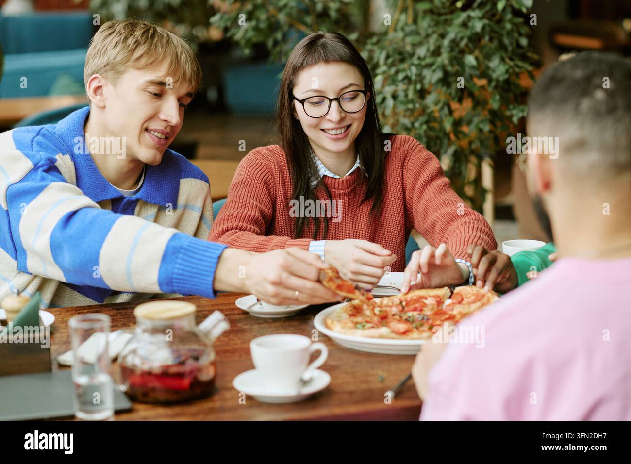 Multikulturelle Freunde teilen Pizza und essen zu Mittag im Café Stockfoto