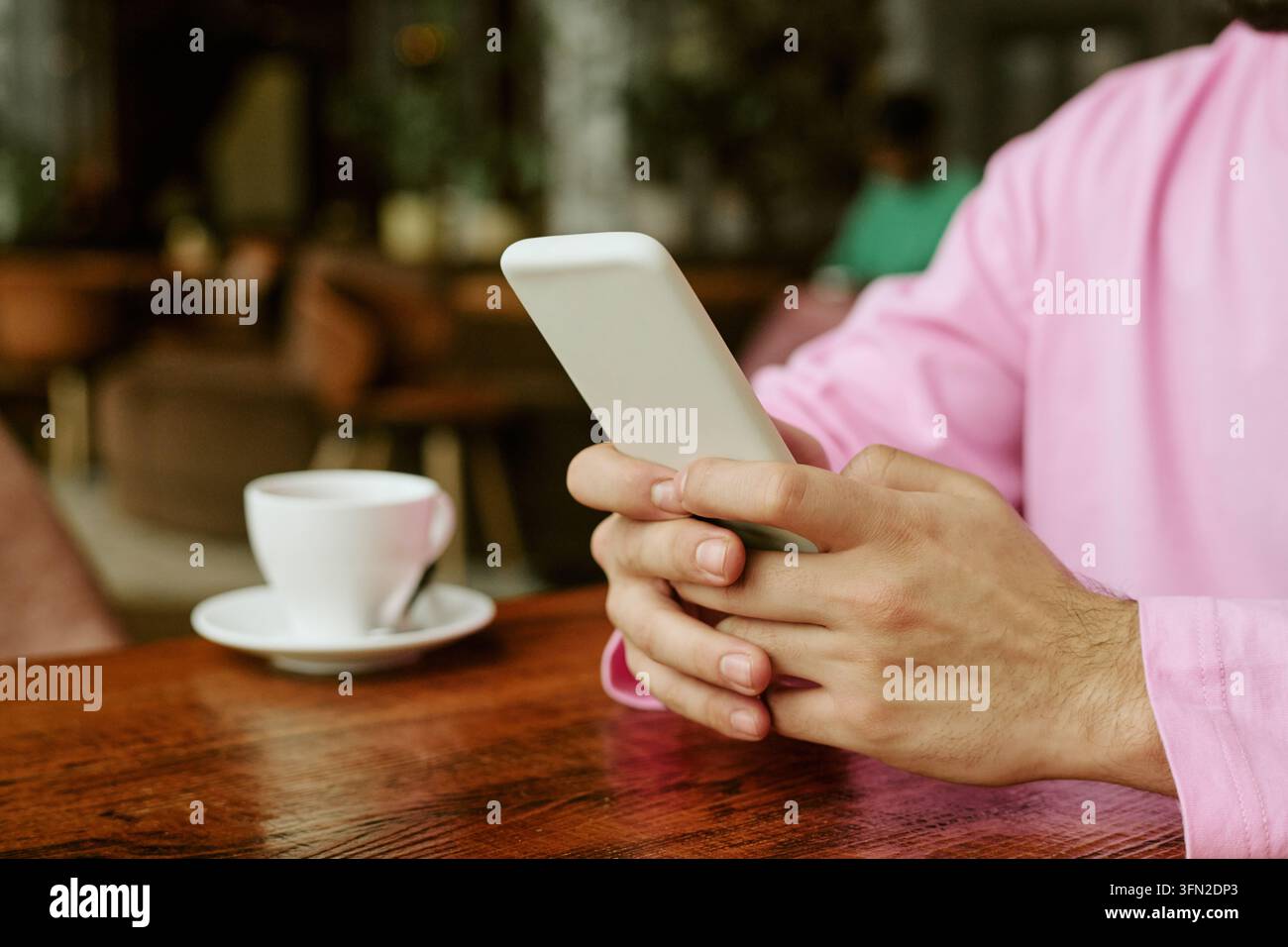 Hände eines Mannes, der ein Smartphone benutzt, während er in einem Café sitzt Stockfoto
