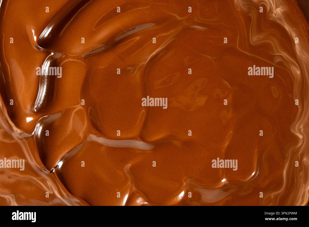 Glänzende geschmolzene Schokoladenwellen abstrakter Hintergrund vertikale Makroaufnahme. Stockfoto