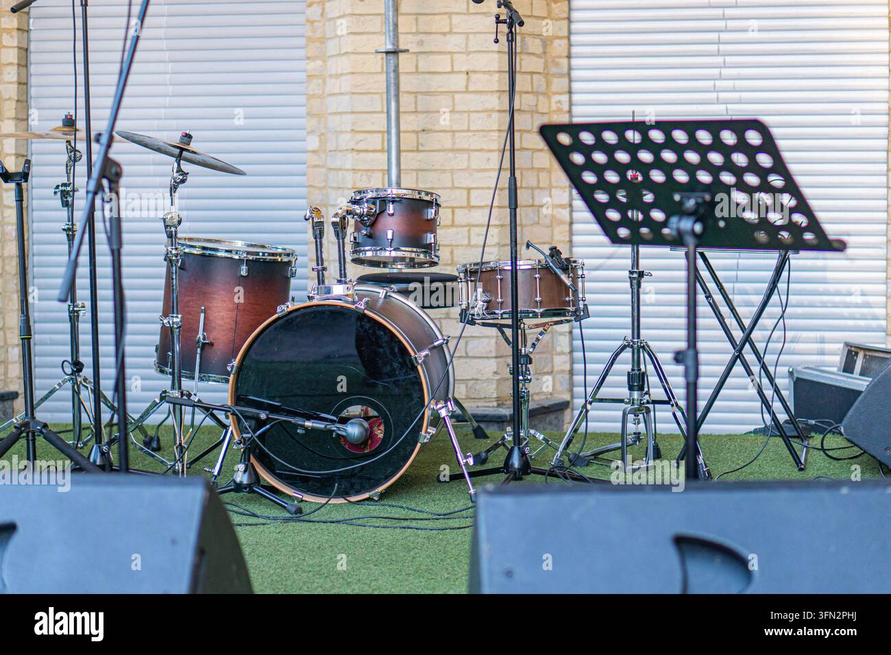 Bühnenaufbau mit Musikinstrumenten, Mikrofonständer, Schlagzeug, Musikständer, künstlicher Beleuchtung, ungezwungener Stil, Live-Performance oder Soundcheck-Sess Stockfoto