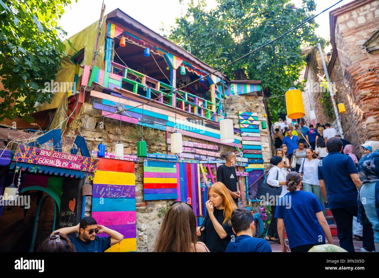 Istanbul, Türkei - 28. August 2026: Bunte Straßenszene in einem lebendigen Viertel mit Menschen, die an bunt bemalten Gebäuden und Dekorationen vorbeigehen Stockfoto