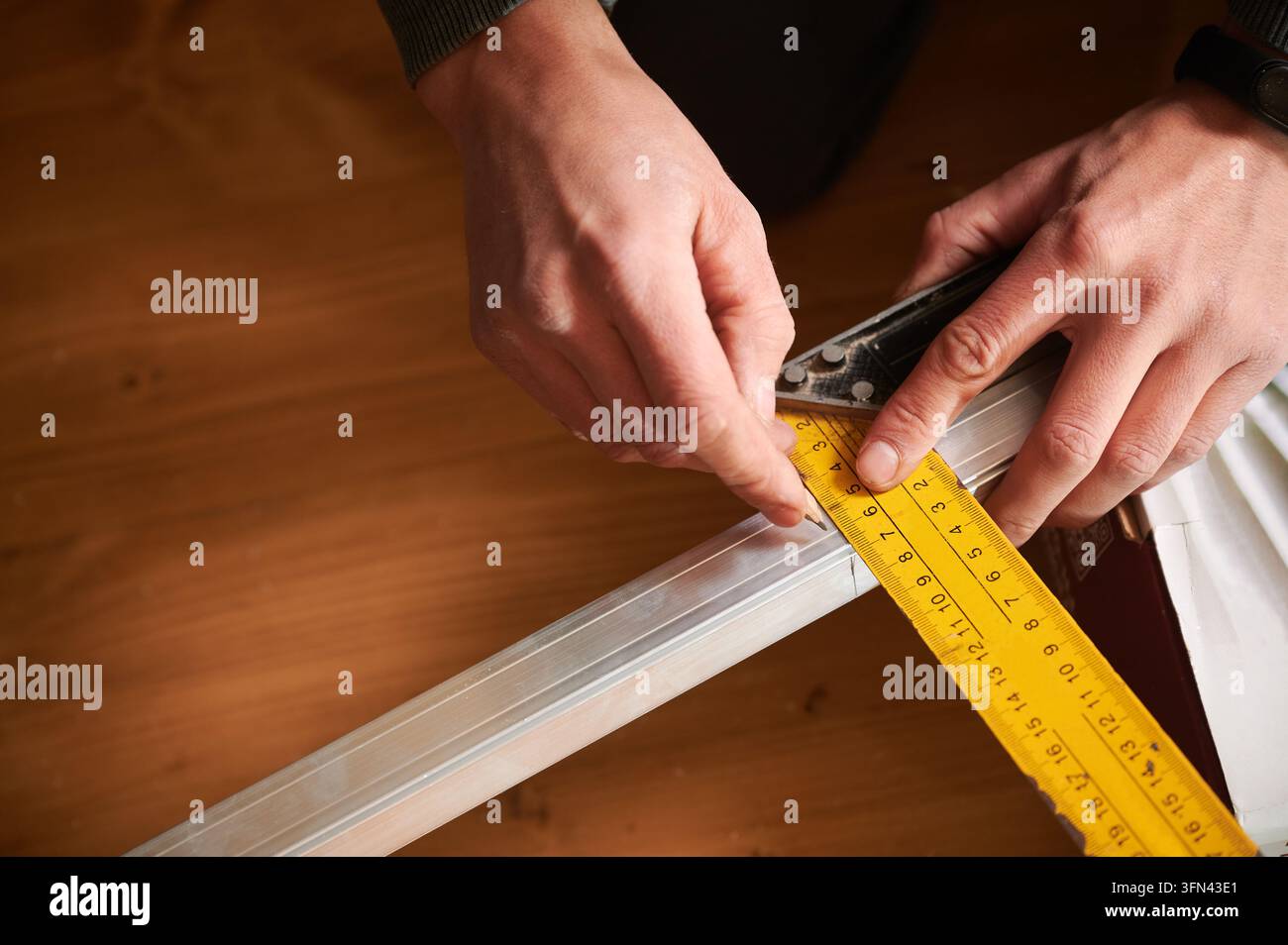 Mann markiert Maß auf Metallprofil mit Bleistift und Lineal, Nahaufnahme von Händen während der Vorbereitungsarbeit. Innenraum-Arbeitsplatz, präzises Layout und Konstruktionsplanungskonzept Stockfoto