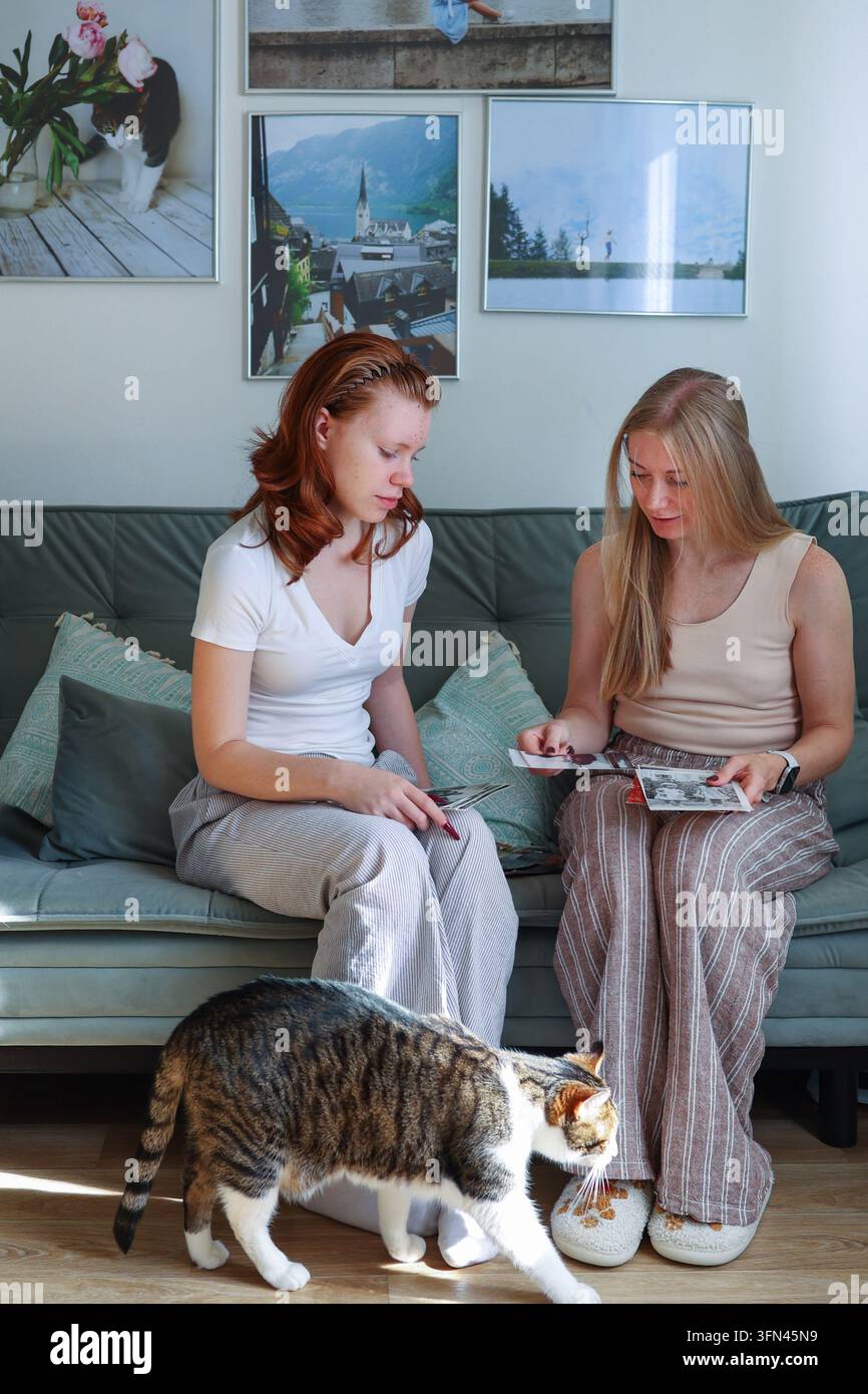 Mutter teilt vintage Familienfotos mit ihrer Tochter, symbolisch für generationenübergreifende Bindungen und die Bewahrung des persönlichen Erbes. Stockfoto