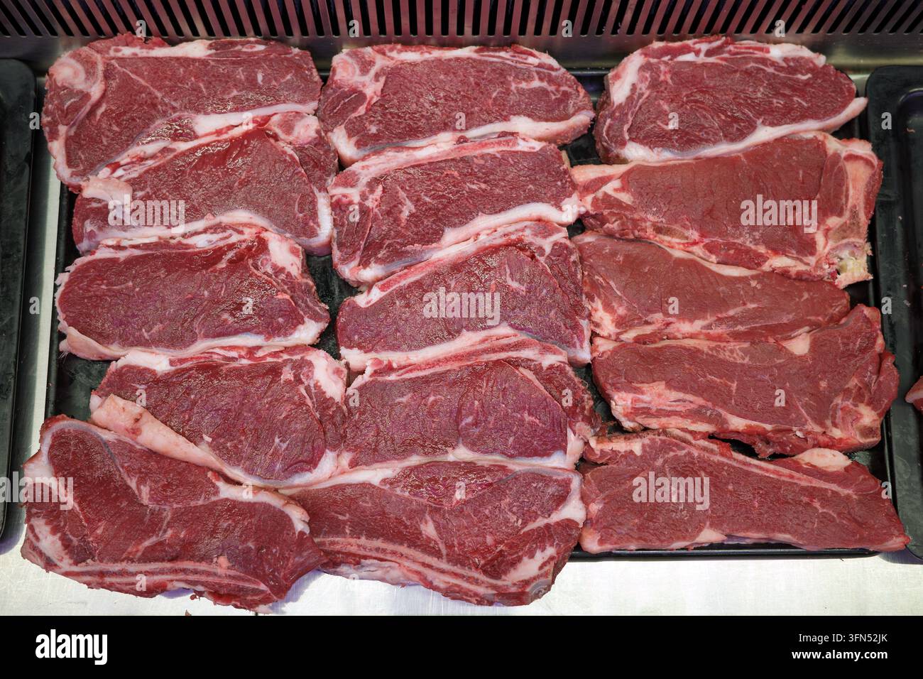 Rohe Rindersteaks, Fleisch, Metzger, Auslage, frisch, rot, Eiweiß, Schnitte, Einzelhandel, angeordnet auf gekühltem Tresen für Lebensmitteleinkäufe, Lebensmittelpreise, Carnivore-Diät und Fleischindustrie-Konzepte. Stockfoto