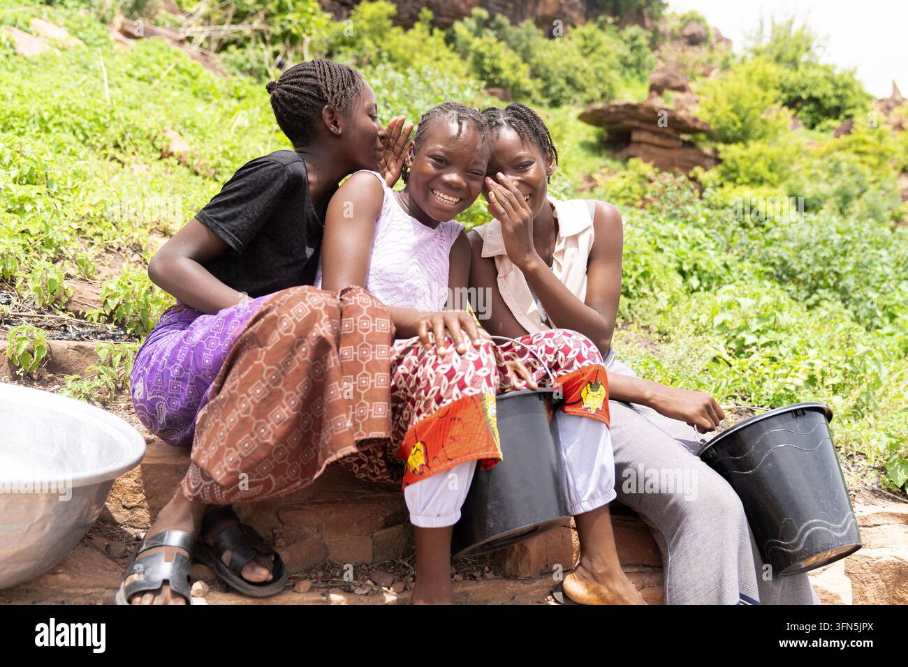 Lächelndes afrikanisches Mädchen springt im Freien neben einem Solarpanel Seil, vereint Kinderspiel, Bewegung, Mädchenbefähigung, erneuerbare Energie und Klimamaßnahmen Stockfoto
