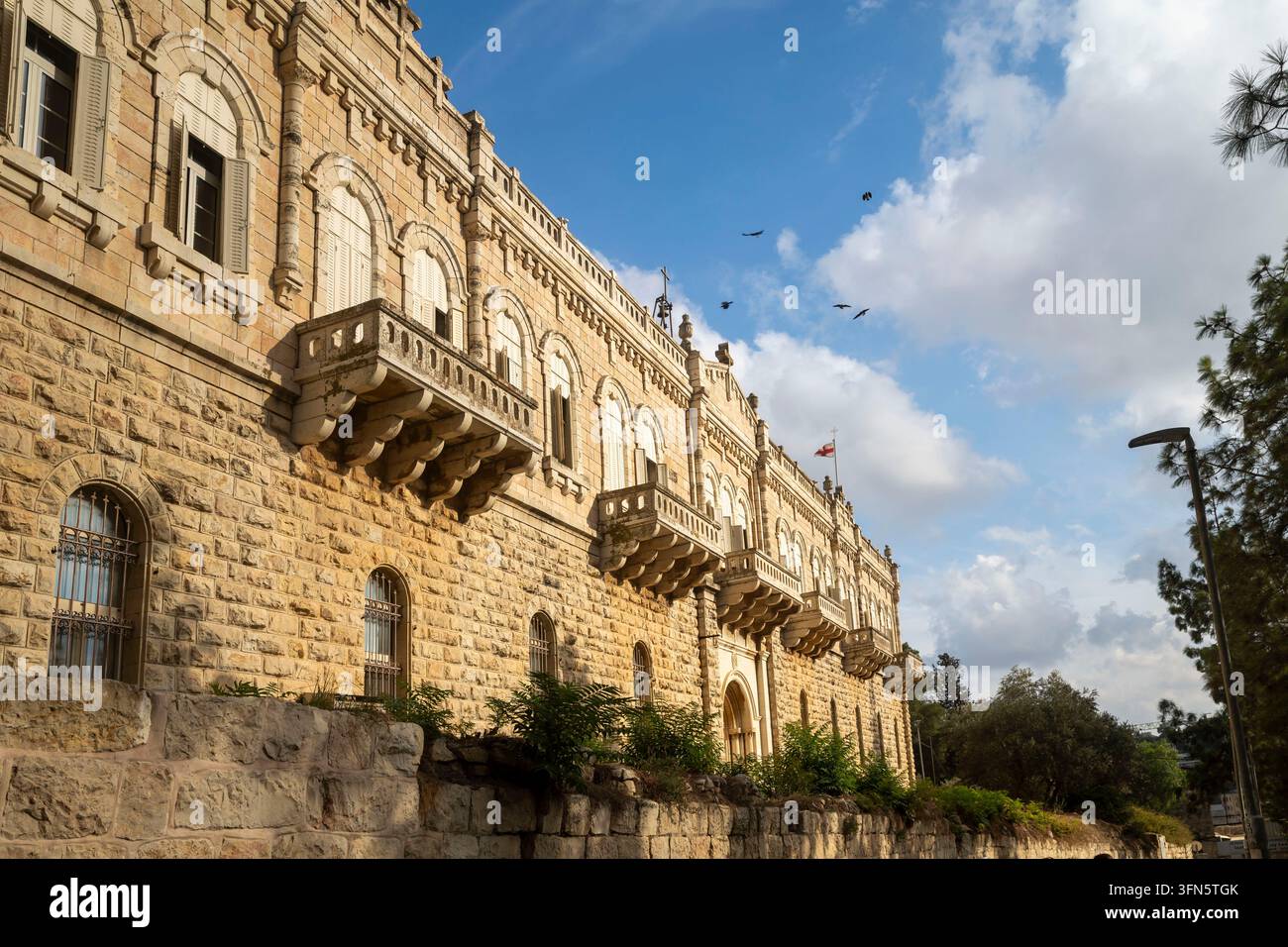 Jerusalem, Israel, 26. September 2026. Historisches Gebäude der Patriarchalen Schule von Zion auf dem Zionberg mit Balkonen, gewölbten Fenstern und wieder fliegenden Vögeln Stockfoto