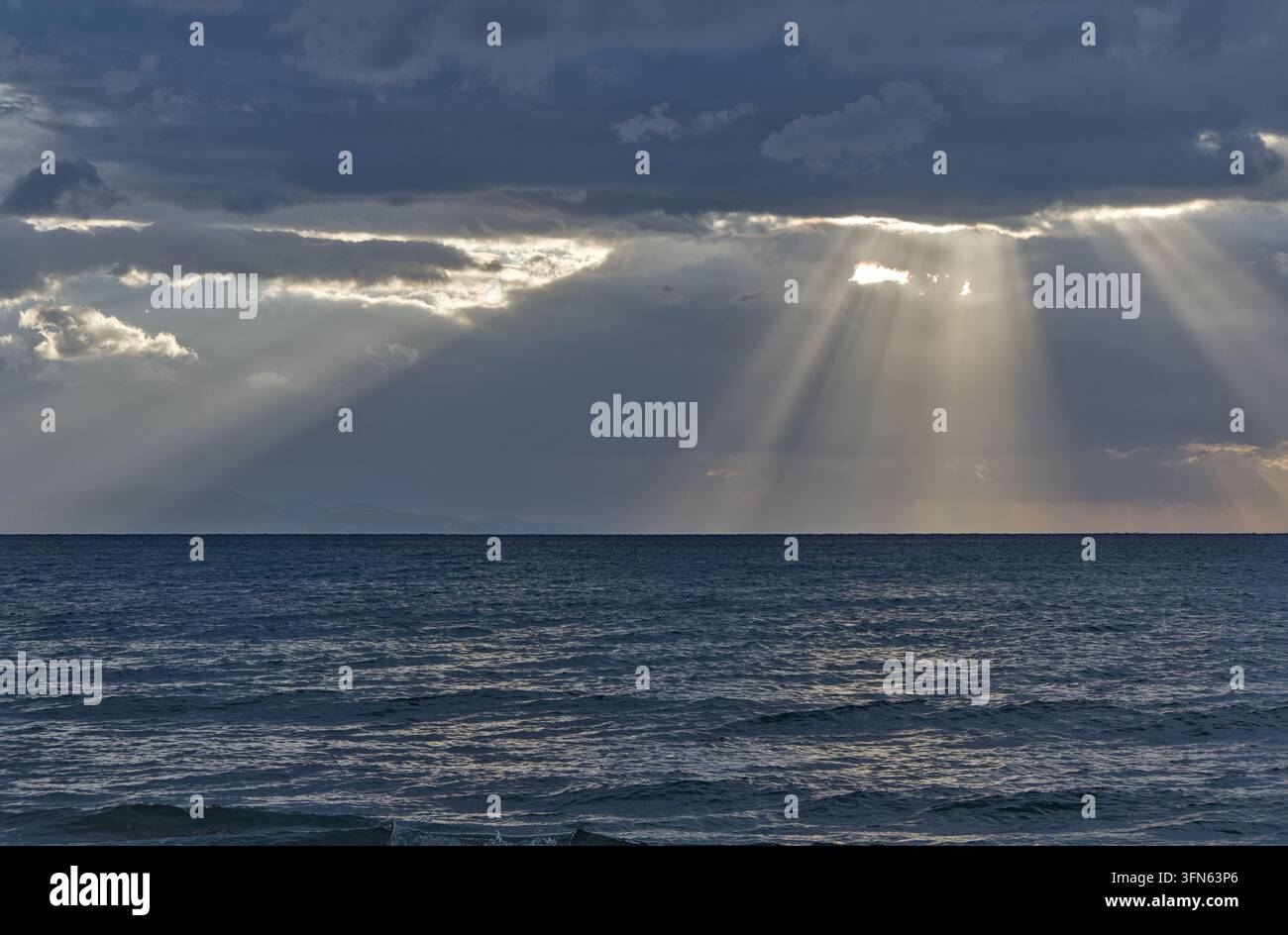Sonnenstrahlen brechen durch dramatische Wolken über dem Meer, gesehen von Artemida, Ostattika, Griechenland. Stockfoto