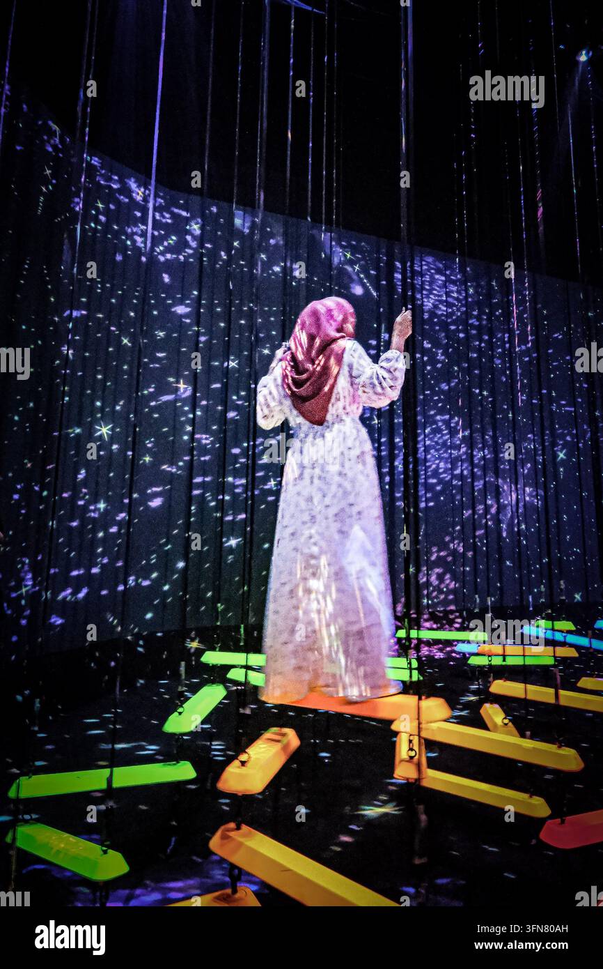 Frau, die eine immersive digitale Lichtinstallation erlebt. Stockfoto