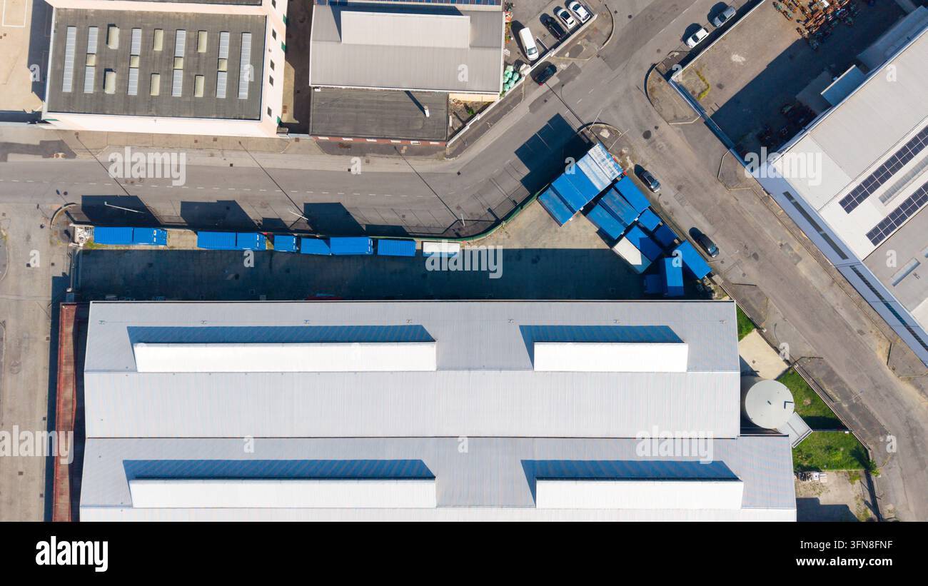 Luftaufnahme von Industriegebäuden mit Metalldächern und blauen Versandcontainern im Produktionsgebiet von Mailand, Lombardei, Italien. Stockfoto