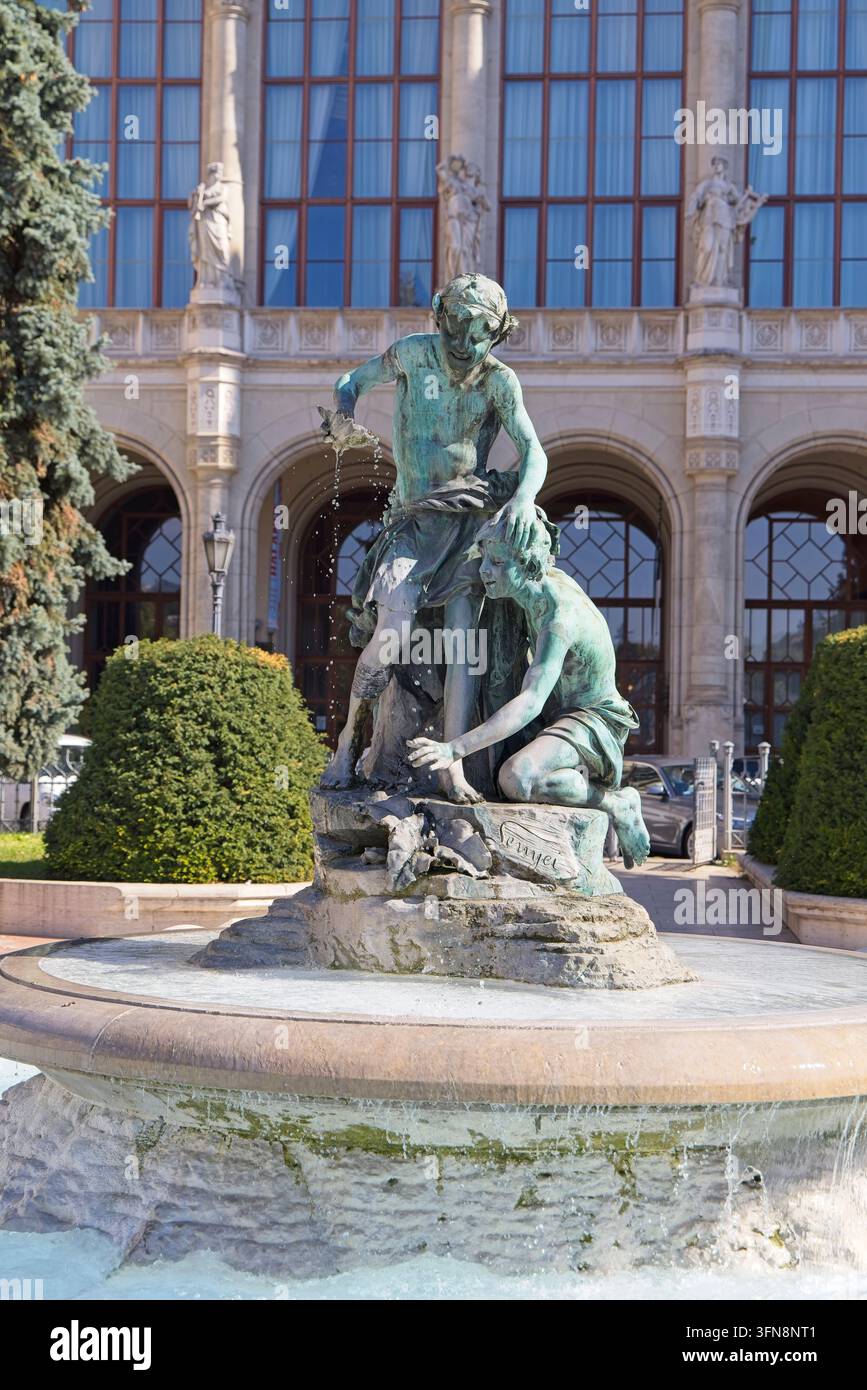 Der kunstvolle Brunnen auf dem Vigadó-Platz in Budapest, Ungarn, mit einer grünen Bronzeskulptur von Figuren auf einem Stein Sockel unter einem klaren blauen Himmel. Stockfoto