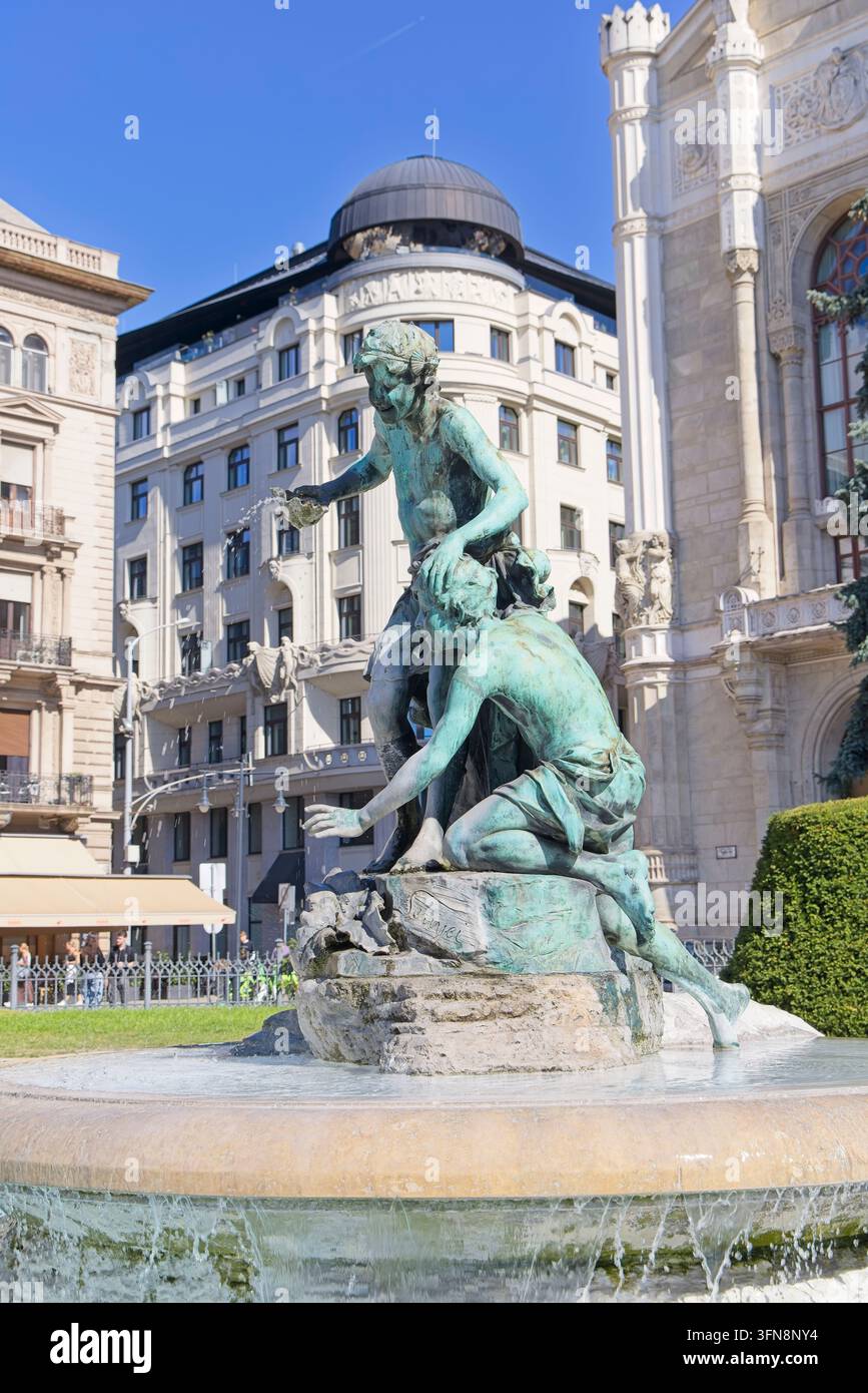 Der kunstvolle Brunnen auf dem Vigadó-Platz in Budapest, Ungarn, mit einer grünen Bronzeskulptur von Figuren auf einem Stein Sockel unter einem klaren blauen Himmel. Stockfoto