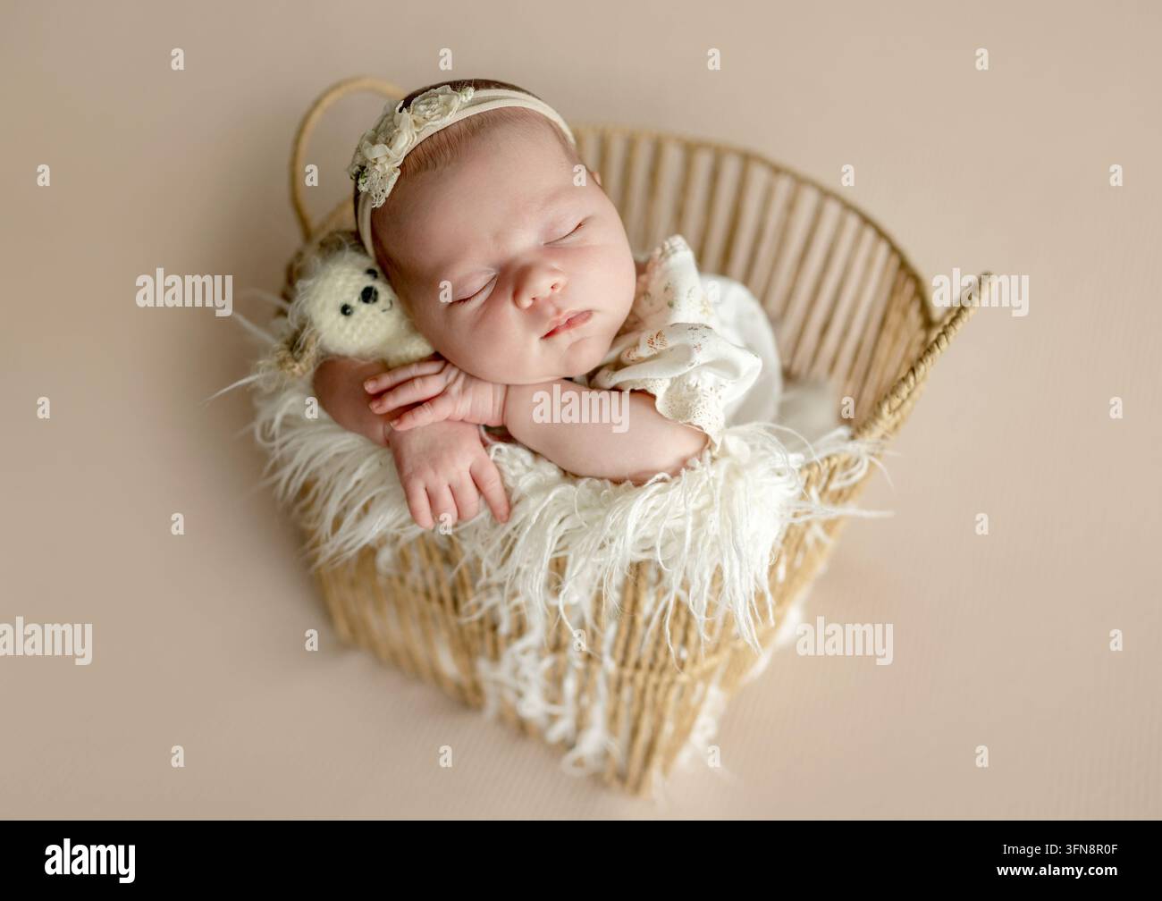 Neugeborenes Mädchen schläft friedlich in einem geflochtenen Korb. Stockfoto