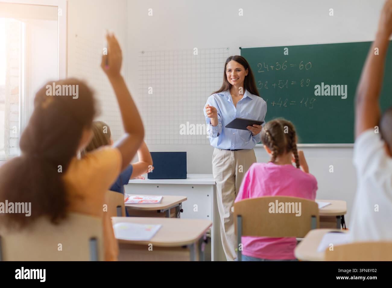 Lehrerin führt Mathematikunterricht an der Vorderseite eines hellen Klassenzimmers Stockfoto