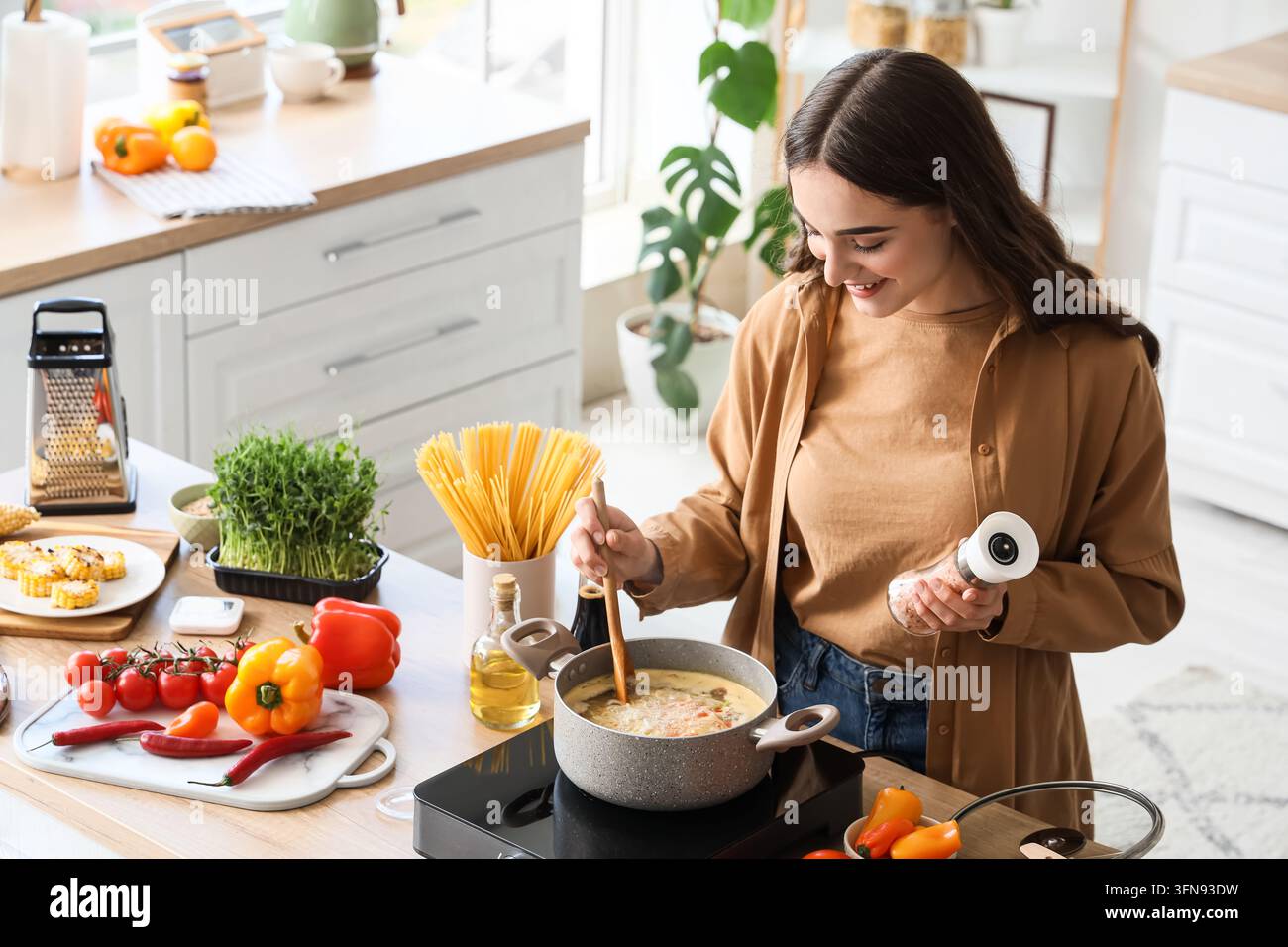 Gesunde Küche und Heimstil, junge Frau bereitet eine frische Mahlzeit mit Gemüse und Gewürzen in einer modernen Küche für ausgewogene Ernährung und Wohlbefinden zu Stockfoto