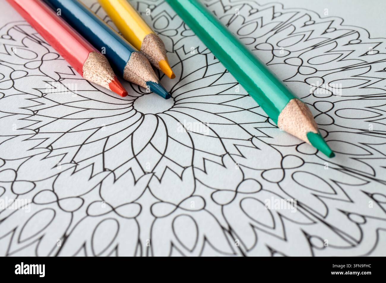 Bunte Buntstifte, die auf einer kunstvollen leeren Mandala-Farbseite platziert sind, kreative Komposition zum Ausmalen, Zeichnen, Kunst, Entspannung, Achtsamkeit Stockfoto
