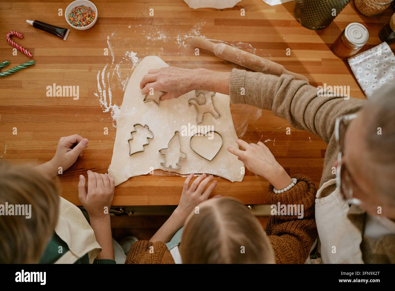 Seniorin mit Kindern, die zu Hause Feiertagsplätzchen backen Stockfoto