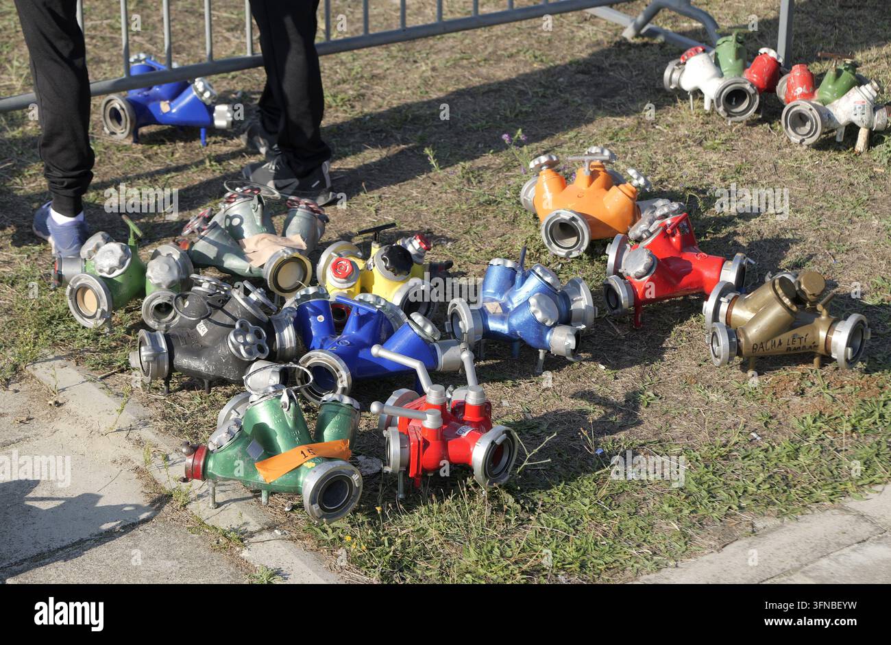 Feuerwehrgeräte, darunter mehrere farbenfrohe Schlauchverteiler und Manifold, liegen bereit auf dem Rasen für einen Feuerwehrwettbewerb oder eine Schulung e Stockfoto