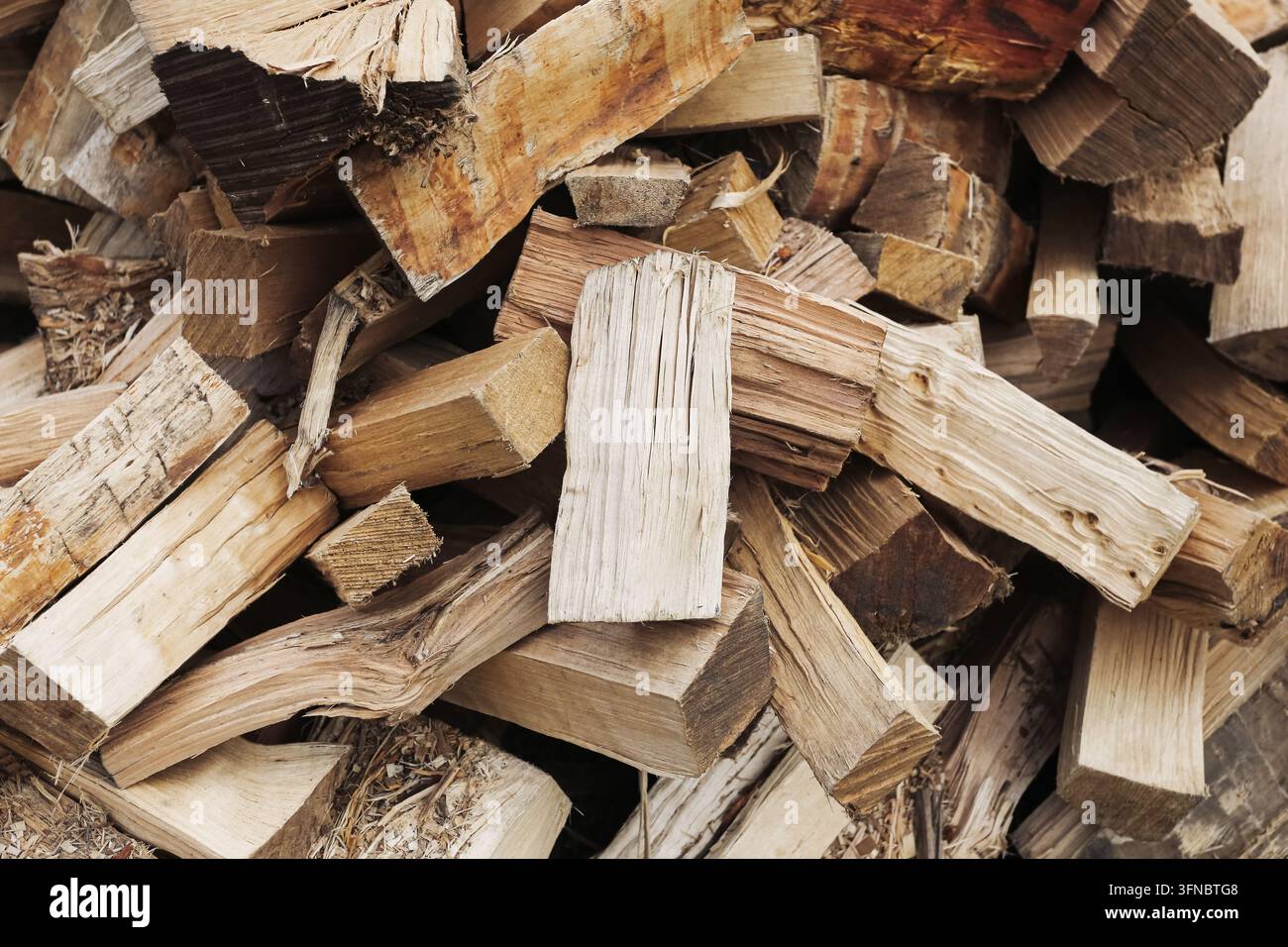 Haufen gehackter Feuerholzblöcke im Freien. Heizhintergrund für Holzofenofen Winterenergie Biomasse und Haushaltswärme. Stockfoto