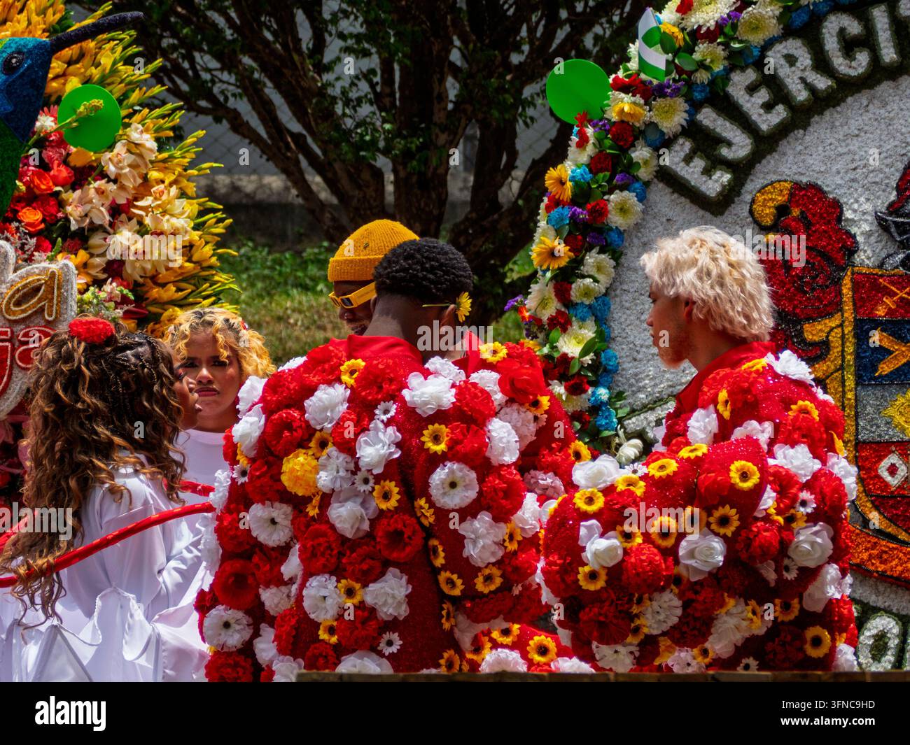 Eine Gruppe von Darstellern in leuchtenden roten, gelben und weißen Blumenkostümen versammelt sich während der Feria de las Flores (Festival der Blumen) Stockfoto