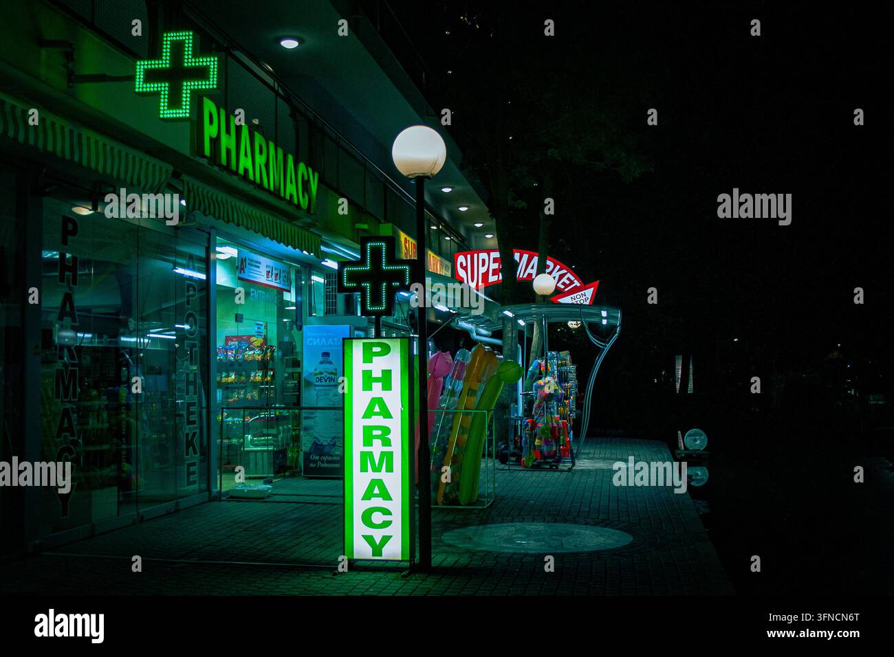 Eine Apotheke, die spät in der Nacht geöffnet hat, mit leuchtend bunten Neonschildern in Sunny Beach, Bulgarien Stockfoto