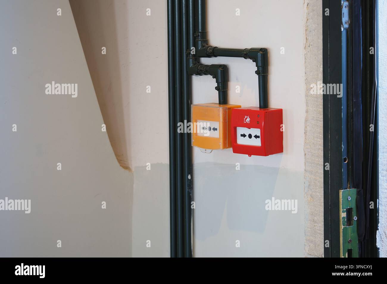 Rote und orangefarbene elektrische Schalter, die an einer Wand in einem Gebäude montiert sind Stockfoto