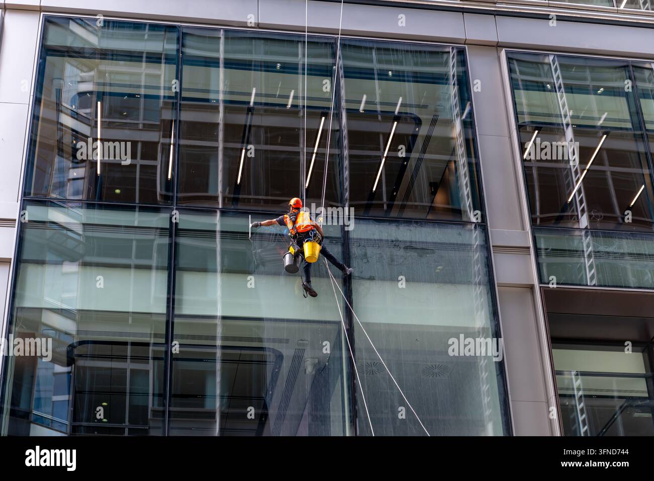 London. UK- 23. September 2026. Ein Fensterreiniger reinigt die Glasfenster eines Hochhaus-Büroblocks in Canary Wharf. Stockfoto