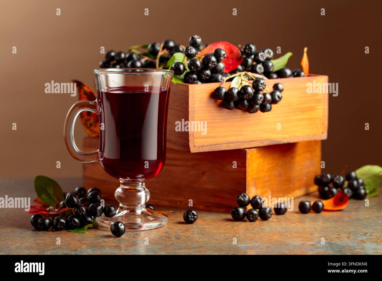 Glas Aroniabeer und frische Beeren in einer Holzkiste. Stockfoto