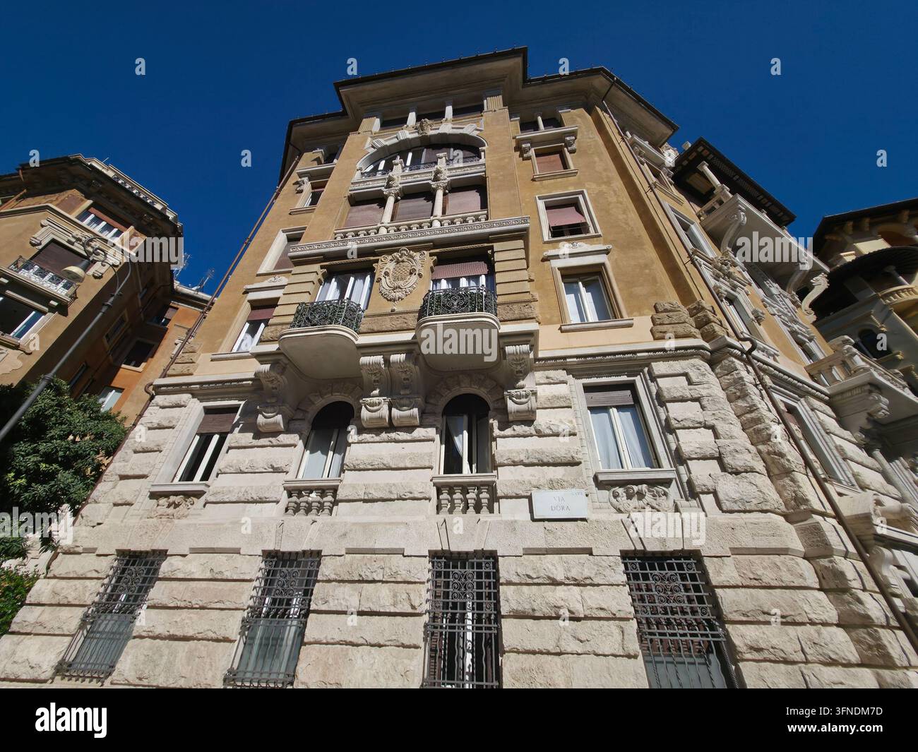 Niedrigwinkelaufnahme eines verzierten Art-Nouveau-Wohnhauses aus dem frühen 20. Jahrhundert mit rustizierter Steinbasis und dekorativen Eisenbalustraden in Rom. Stockfoto