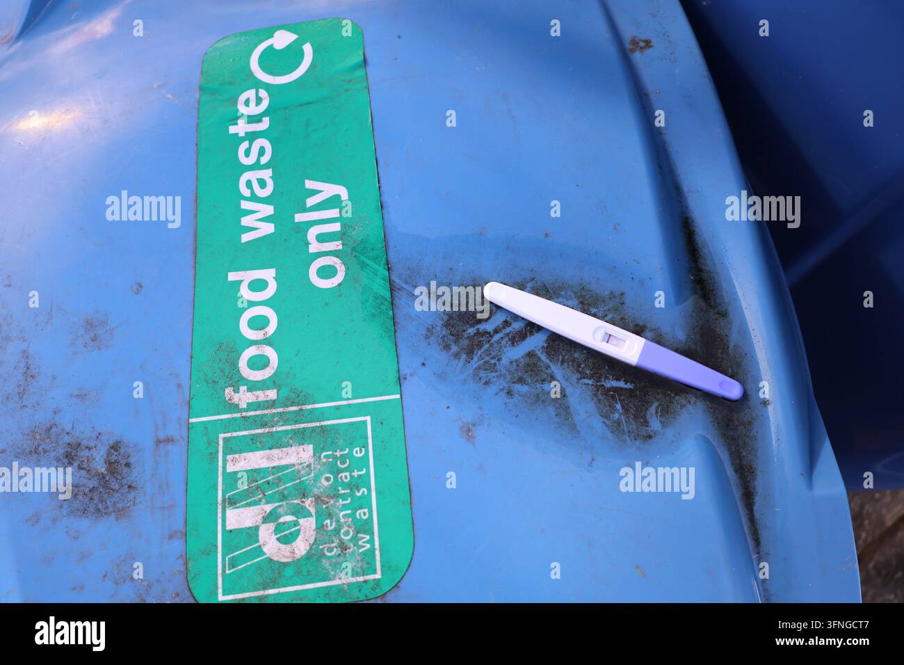 Verworfenes Heimtestgerät, das auf einem nur für Bioabfall vorgesehenen Recyclingbehälter liegt. Stockfoto