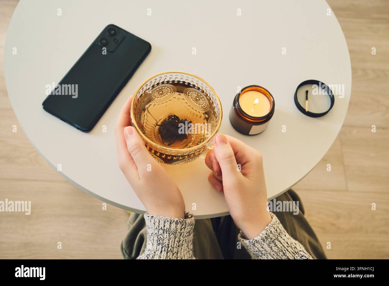 Gemütliches Abendritual mit Tee und Kerzenlicht. Digitaler Detox-Konzept Stockfoto