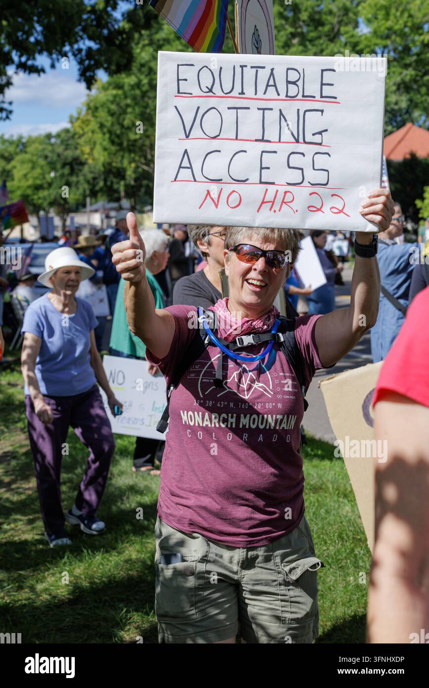 Saint Paul, Minnesota, USA - 17. Juli 2025: Lächelnde Aktivistin gibt Daumen hoch mit Schild „Equitable Voting Access No H.R. 22“ bei einer Anti-Trump-Kundgebung. Stockfoto