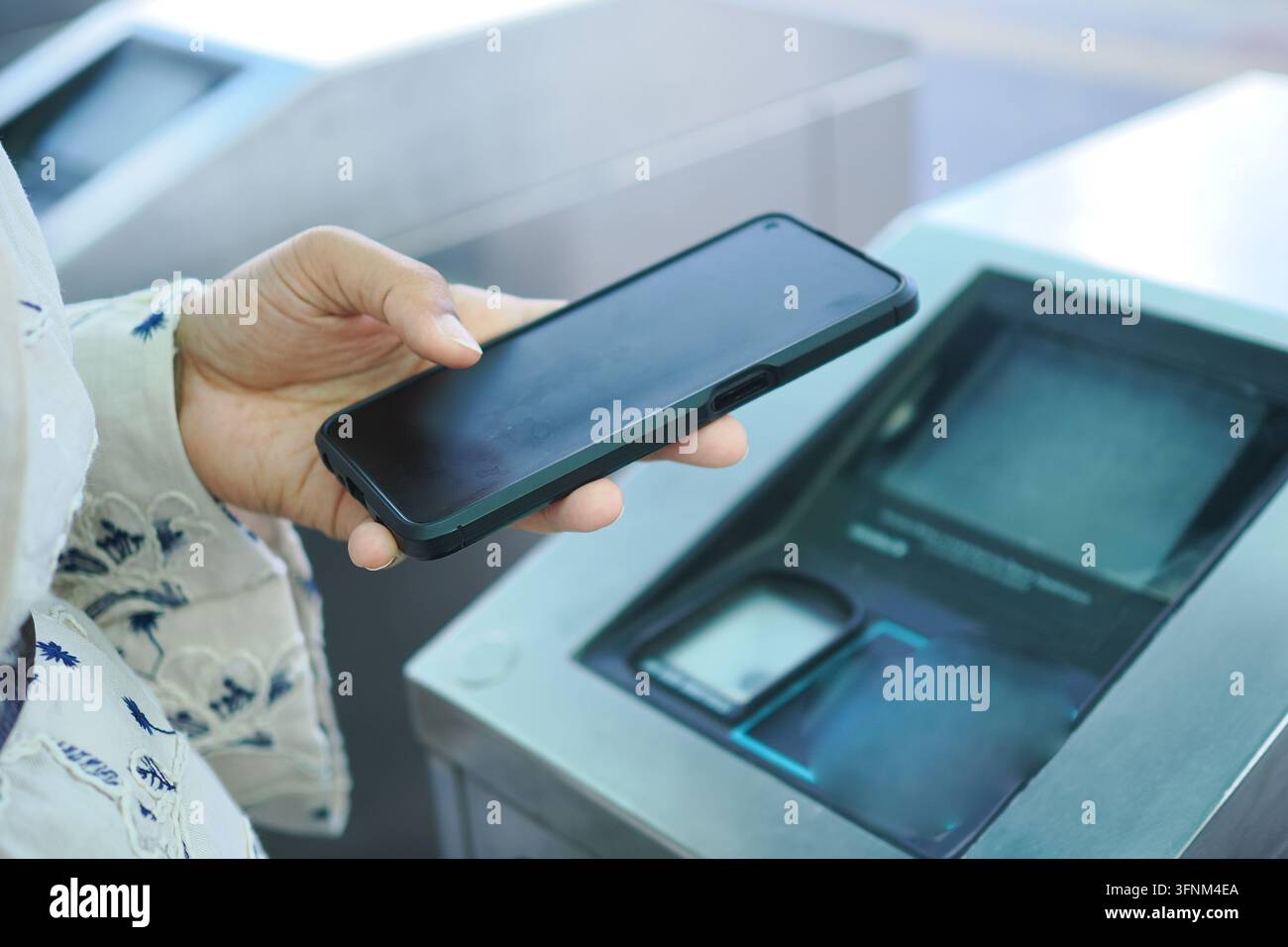 Das Bild zeigt eine Person, die ein Smartphone für einen kontaktlosen NFC-Scan an einem öffentlichen Terminal verwendet Stockfoto