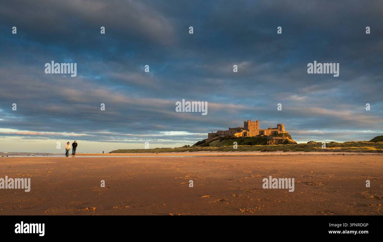 Paar spaziert am Strand nahe Bamburgh Castle an der Küste von Northumberland. Stockfoto