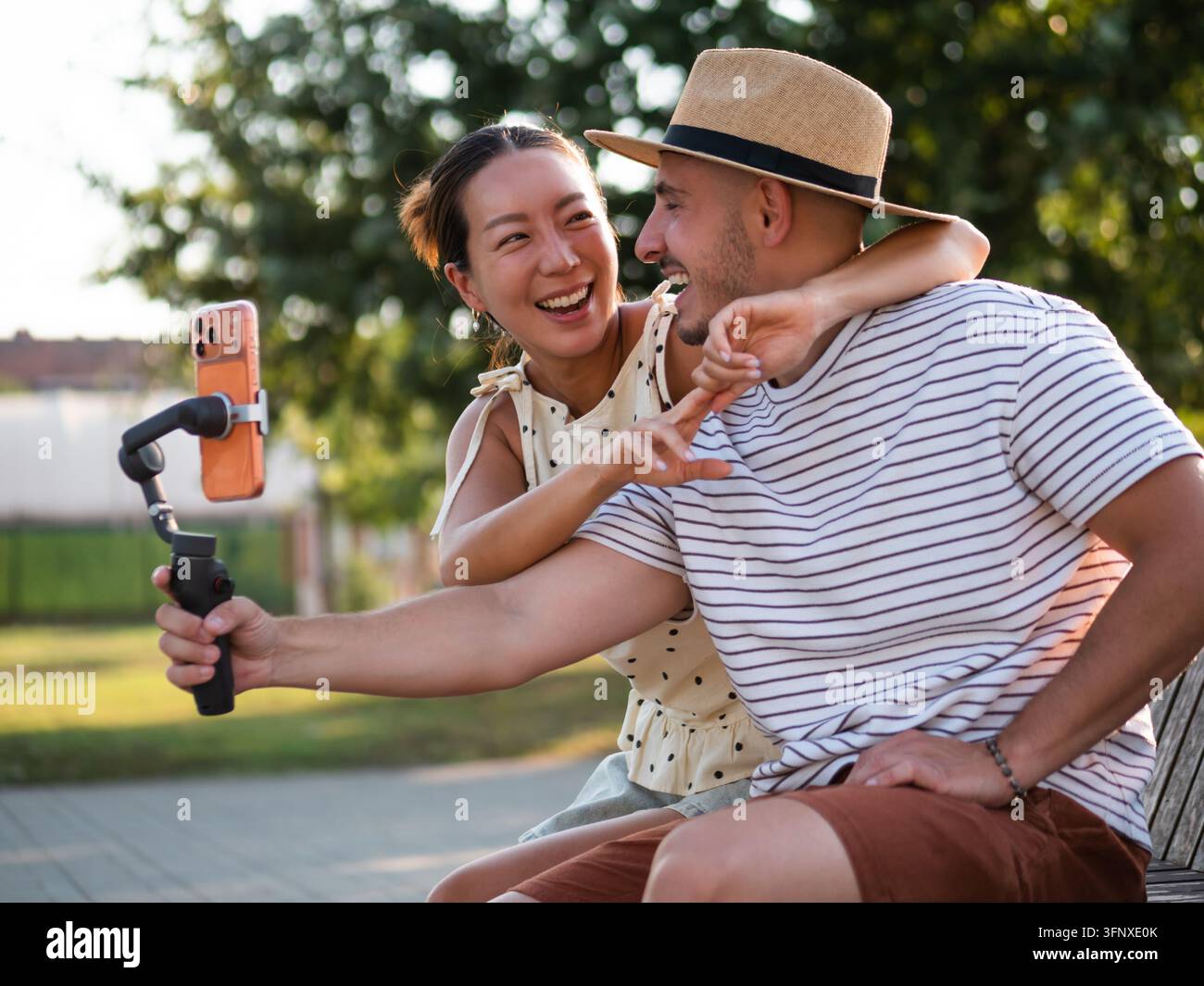 Junger Mann und Frau teilen einen verspielten Moment, während sie Inhalte für soziale Medien erstellen. Stockfoto