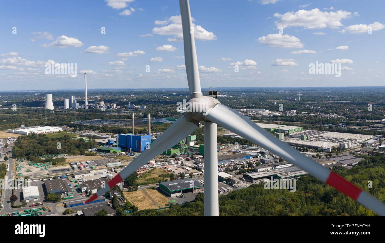 Luftaufnahme einer Windturbine an der Halde Hoppenbruch mit Blick auf eine Industrielandschaft und ein Kraftwerk unter einem blauen Himmel in Herten, Nordrhein-Westfalen Stockfoto
