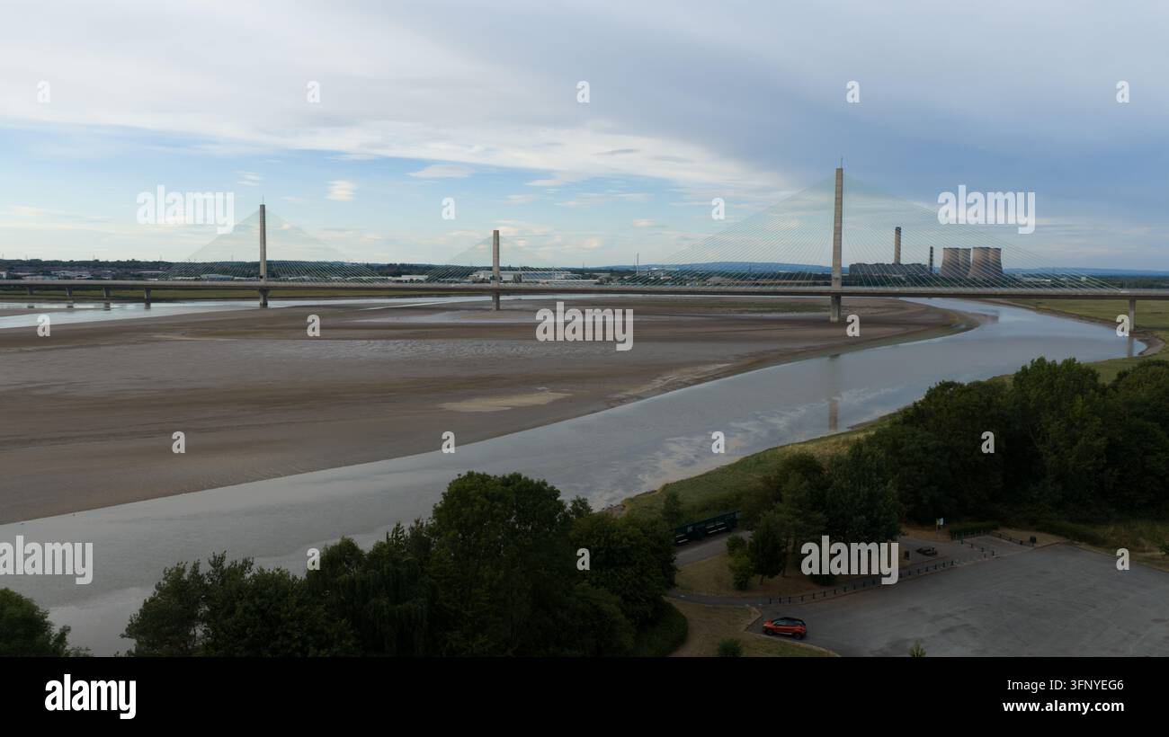 Luftaufnahme der Mersey Gateway Bridge, die bei Ebbe die River Mersey überspannt, mit industriellen Kühltürmen im Hintergrund in Runcorn, England, U Stockfoto