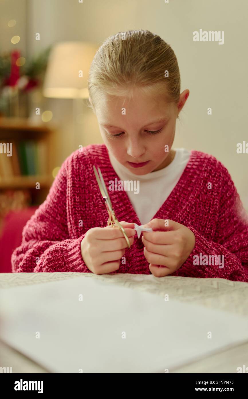 Mädchen schneidet Papier mit einer Schere für eine kreative Bastelaktivität Stockfoto