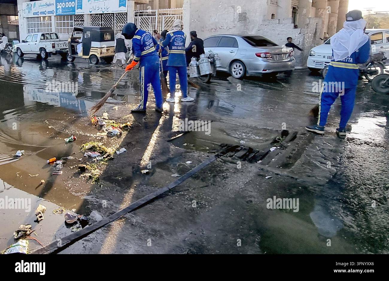 QUETTA, PAKISTAN - 05-Oct-2026: Sanitärmitarbeiter in Quetta waren am Montag aktiv in eine Sauberheitskampagne in Dukani Baba Chowk eingebunden, wie vom Safa Quetta Projekt angewiesen. Die Initiative sah Teams, die überflutete Straßen, die mit Müll übersät waren, einschließlich Plastiktüten und Lebensmitteleinwicklungen, reinigten. Dieser Einsatz ist Teil einer breiteren Strategie zur Bewältigung des Abfallmanagements in der Stadt, was für die öffentliche Gesundheit und Umweltverträglichkeit entscheidend ist. Die Anwesenheit von Fahrzeugen und Fußgängern unterstreicht die Bedeutung der Kampagne für die Aufrechterhaltung der städtischen Mobilität und Hygiene. (Sami Khan/PPI Images) Stockfoto