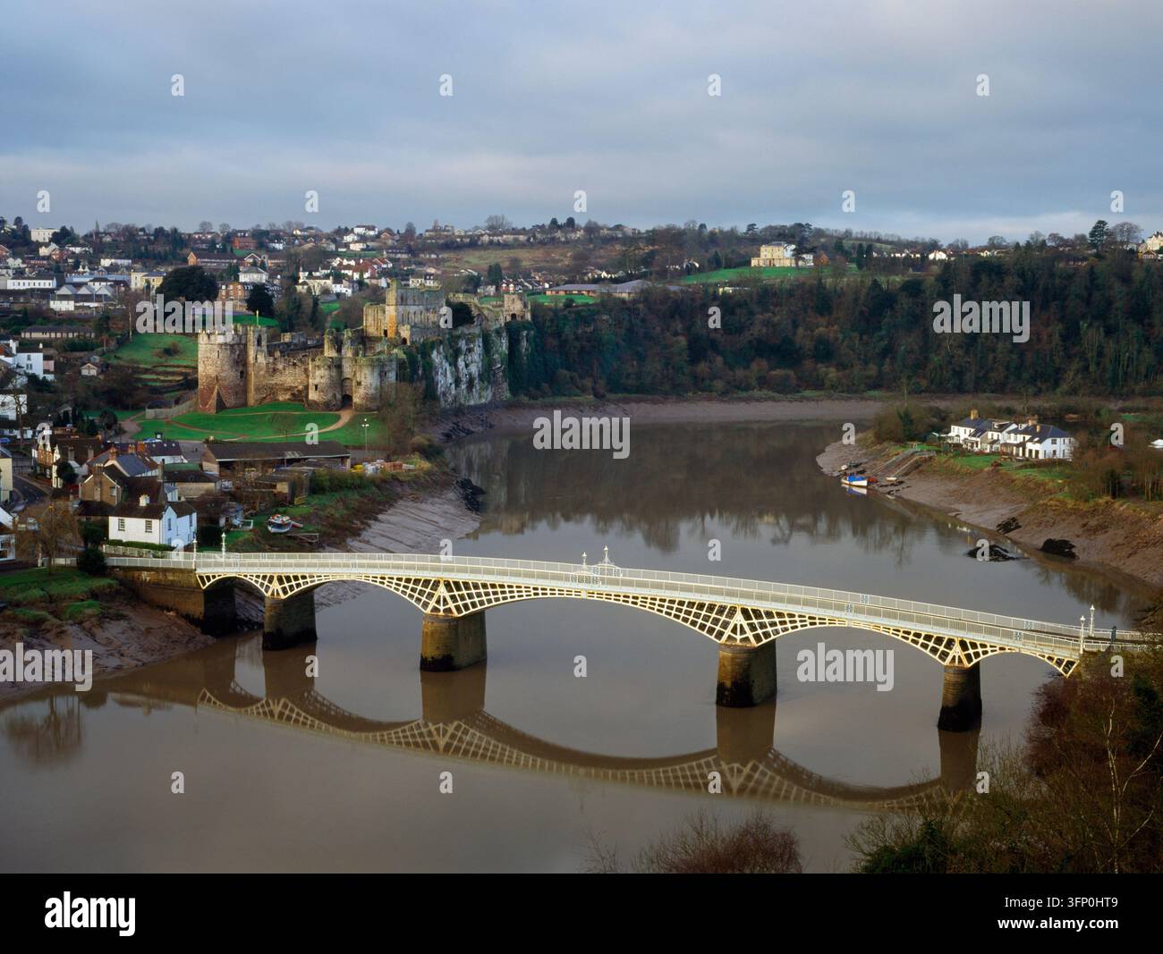 Sehen Sie südwestlich der gusseisernen Bogenbrücke aus dem Jahr 1816 über den River Wye mit Chepstow Castle in Monmouthshire, Wales, Großbritannien, auf der Rückseite. Die Mitte des t Stockfoto