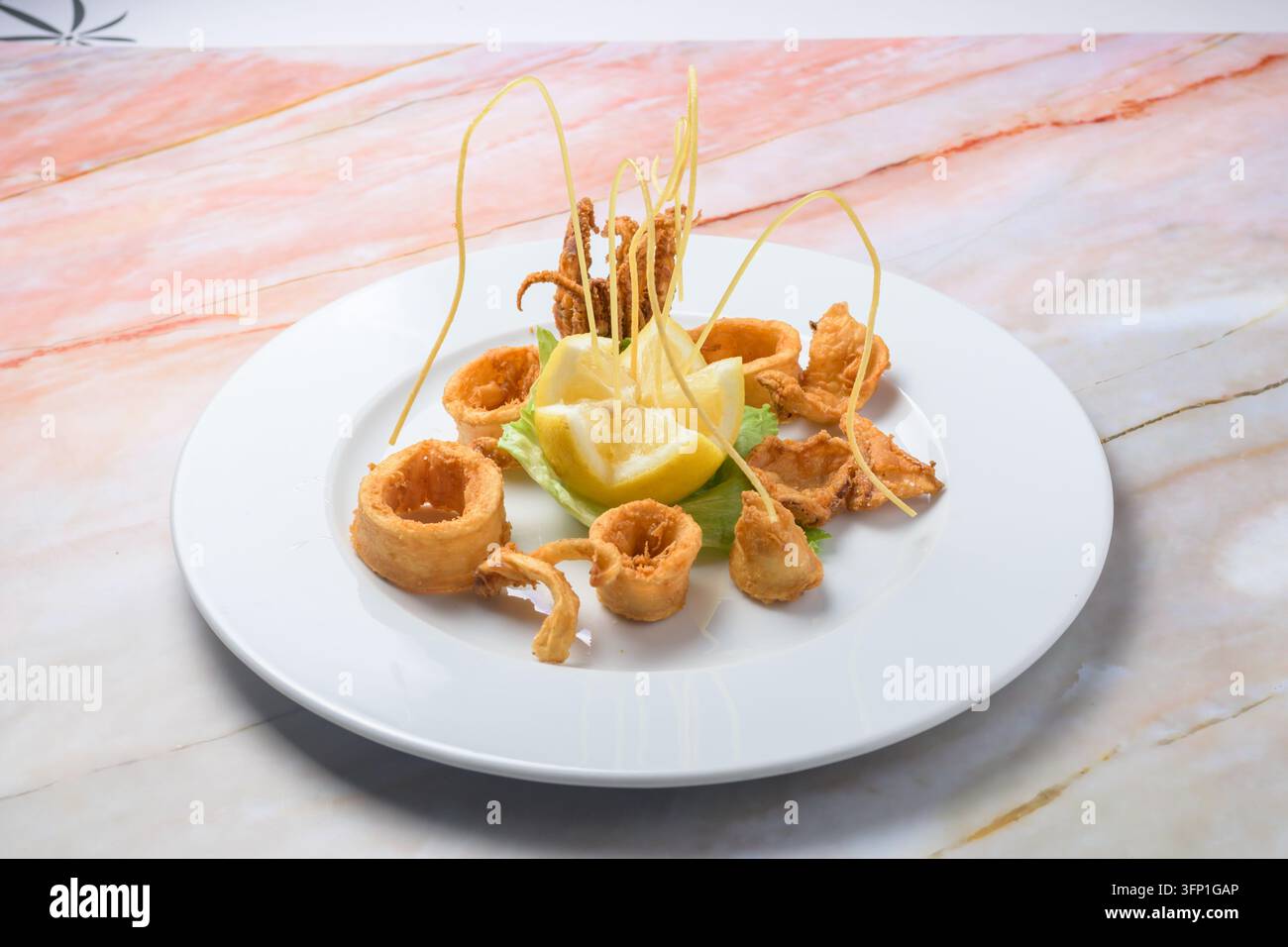 Knusprig gebratene Calamariringe auf weißem Teller serviert Stockfoto