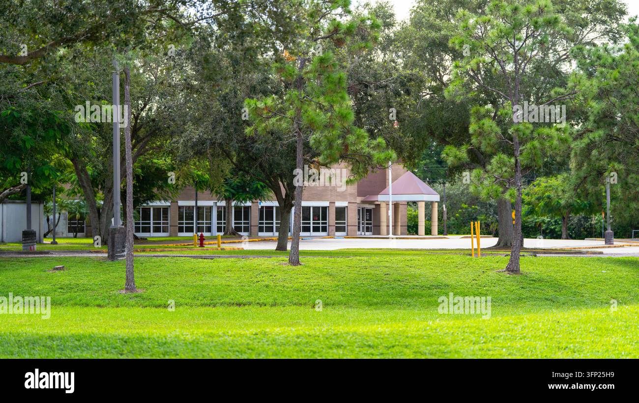 USPS-Postzustellwagen fährt eine ruhige, von Bäumen gesäumte Wohnstraße in Florida mit grünen Rasenflächen und vorstädtischer Umgebung bei Tageslichtansicht. Stockfoto