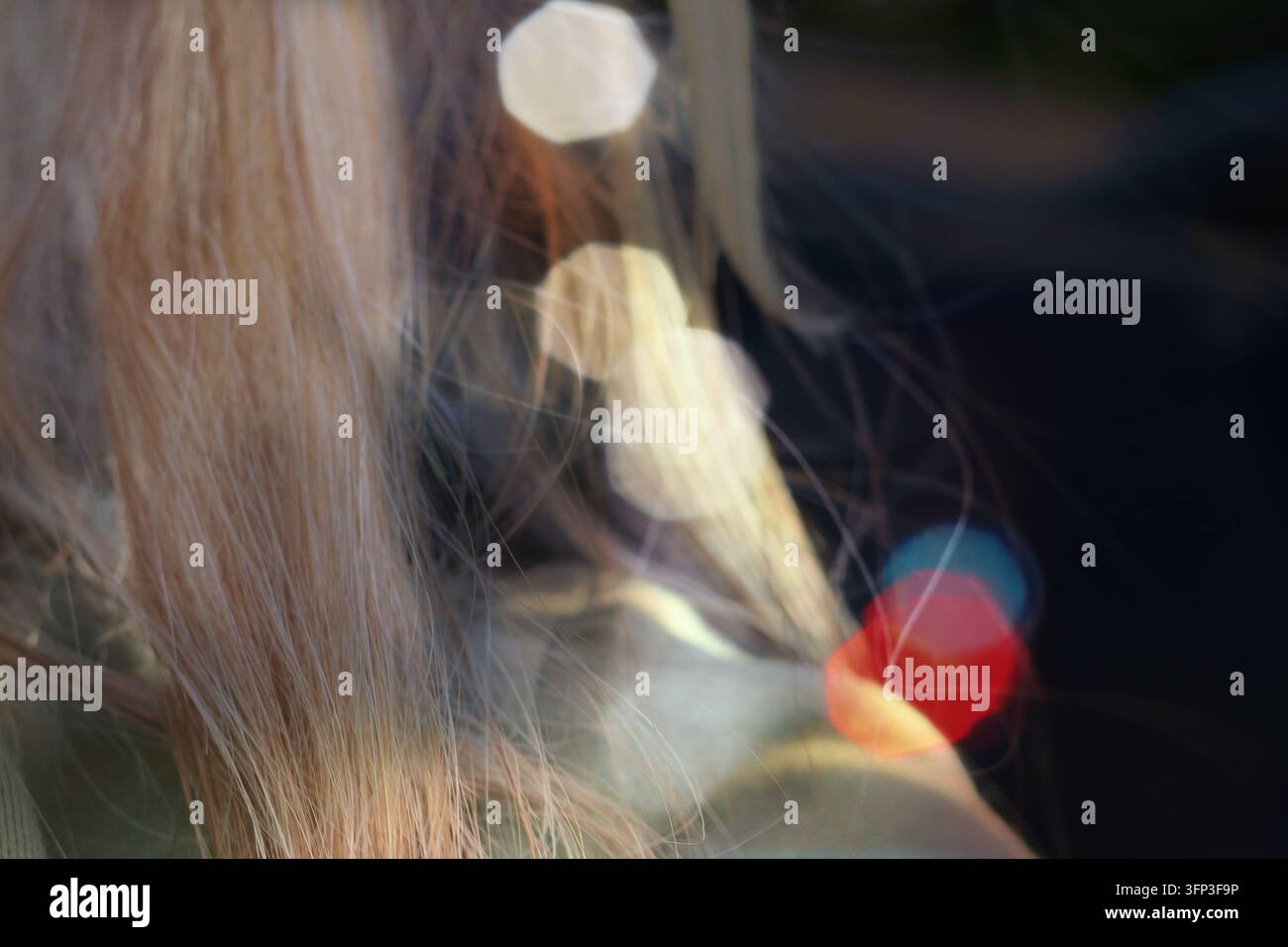 Abstrakter Nahaufnahme von blondem Haar mit bunten Bokeh-Lichtern im Hintergrund Stockfoto
