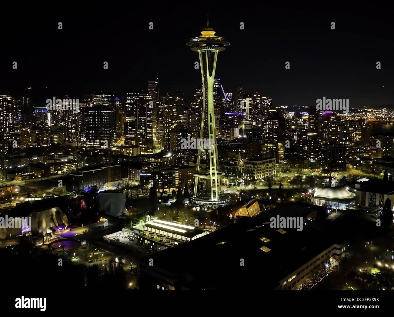 Luftbild des beleuchteten Space Needle, das sich prominent vor der leuchtenden Stadtsilhouette und den urbanen Lichtern der Innenstadt von Seattle, WA, USA abhebt Stockfoto