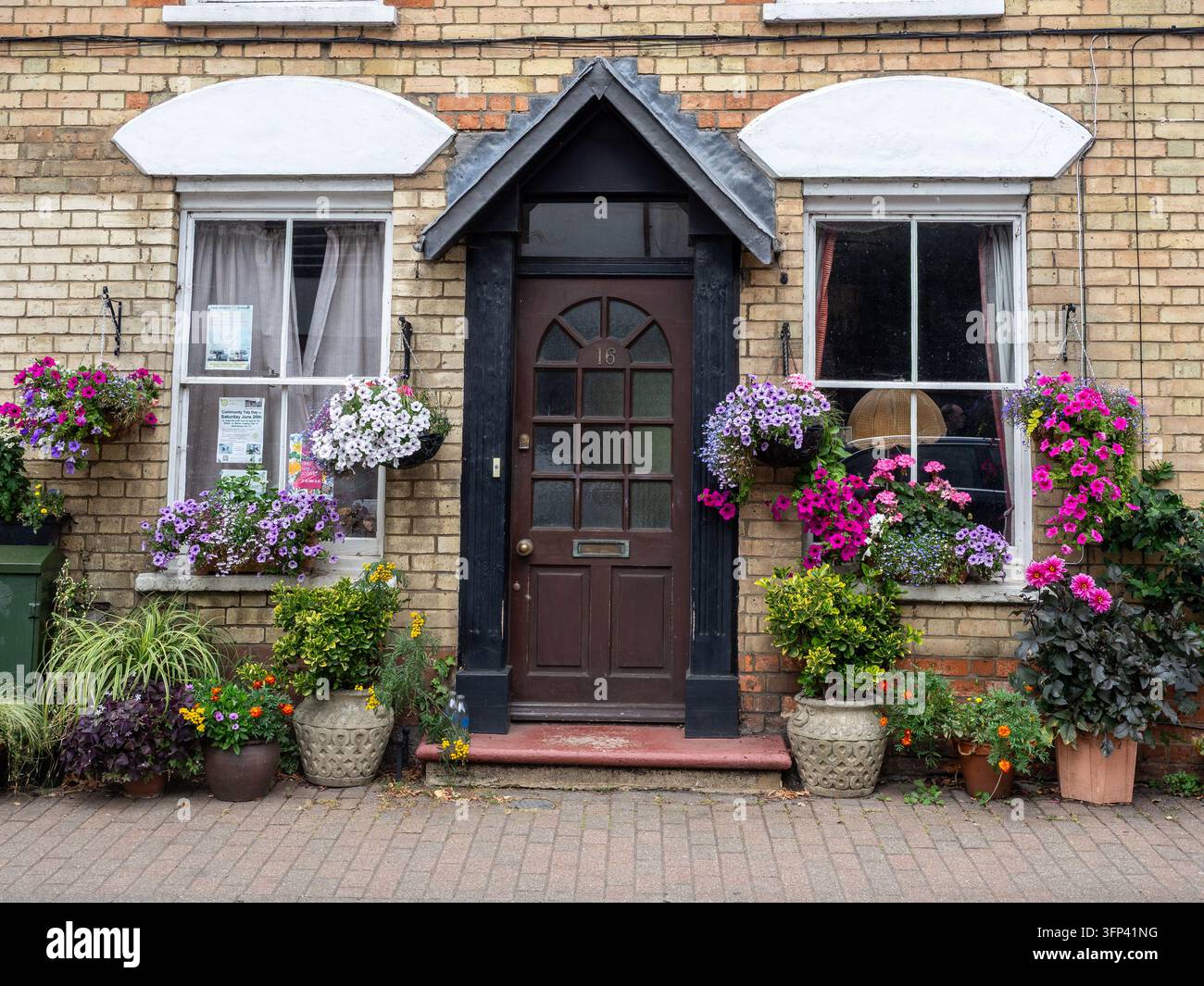 Hausfassade mit bunten Pflanzgefäßen und hängenden Körben, Stadtzentrum, Stony Stratford, Buckinghamshire, UK Stockfoto