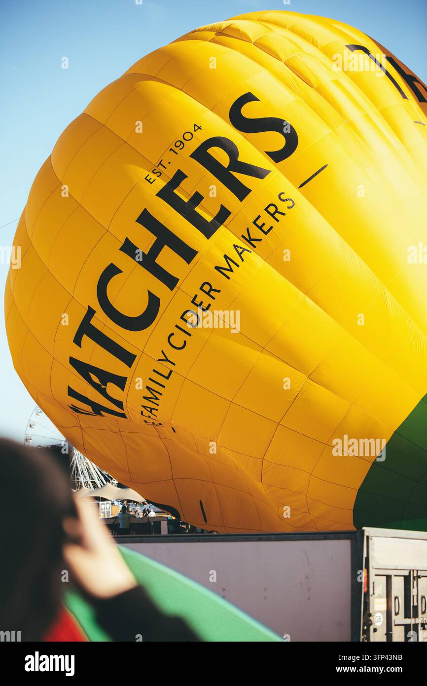 Bristol Balloon Fiesta, 7. August 2026, UK - Nahaufnahme der gelben Thatchers Cider-Hot-Air-Ballonhülle, die auf sonnigen Festplatzflächen aufgeblasen wird Stockfoto
