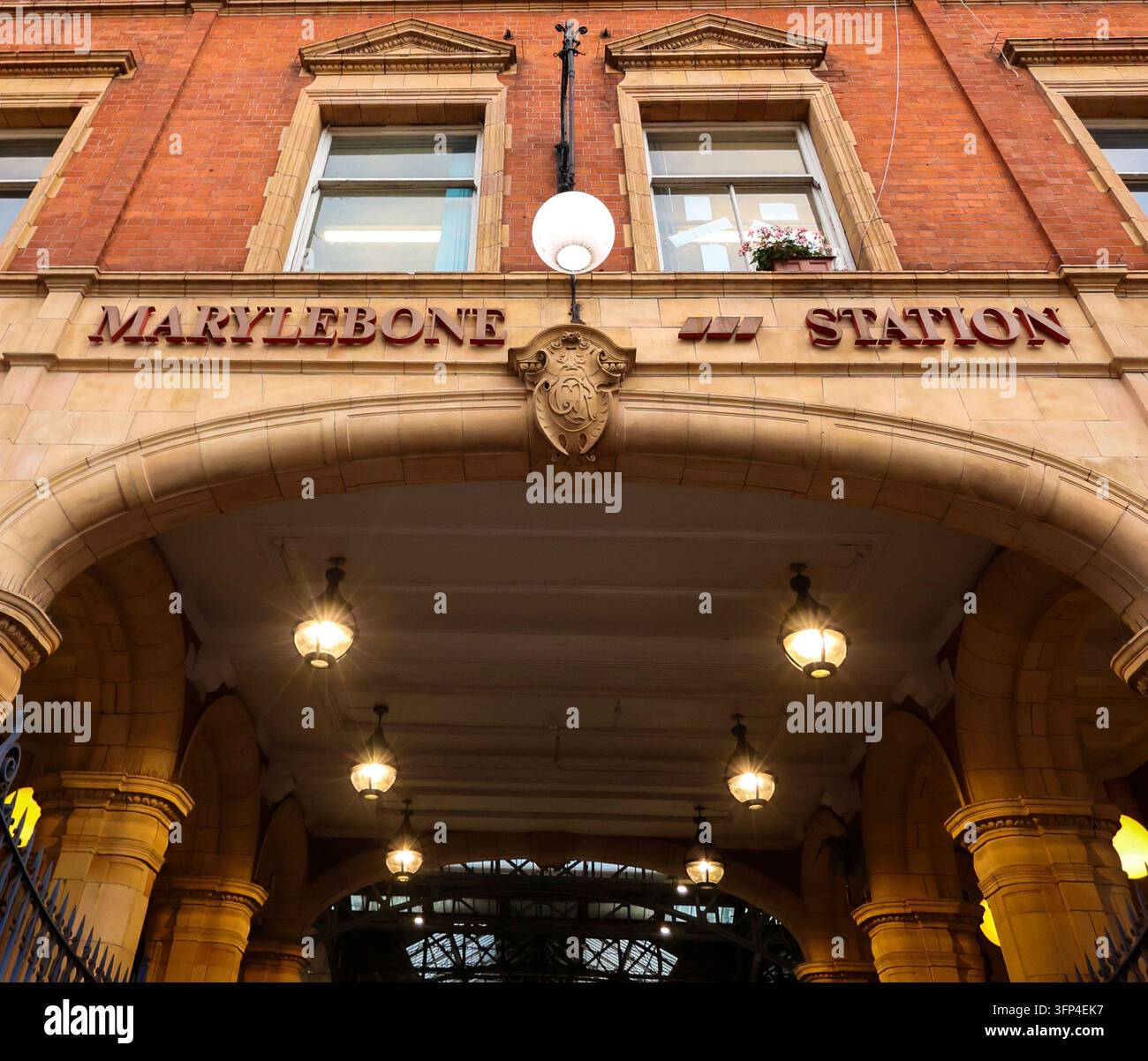 Eingangsbogen der Marylebone Station mit viktorianischer Architektur, Ziegelmauerwerk, Steindetails und leuchtenden Pendelleuchten Stockfoto