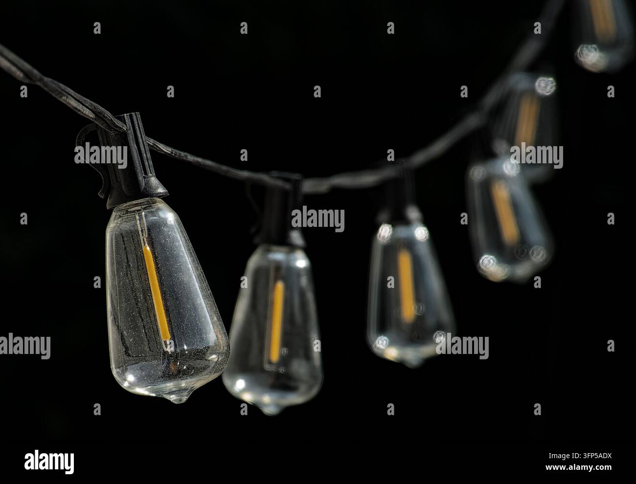 Vintage-Stil ST38/ST40 Outdoor-Edison-Lichterkette mit klaren Glasbirnen und vertikalen LED-Filamenten. Stockfoto