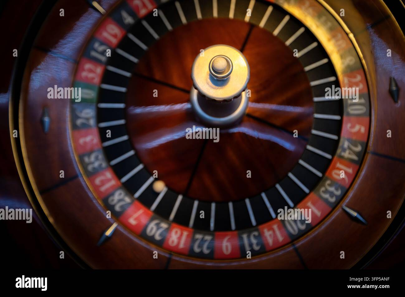 Holz-Roulette-Rad zeigt rote und schwarze Nummerntaschen. Eine kleine Elfenbein-Kugel sitzt während des Casinospiels in der markierten Einlage. Stockfoto
